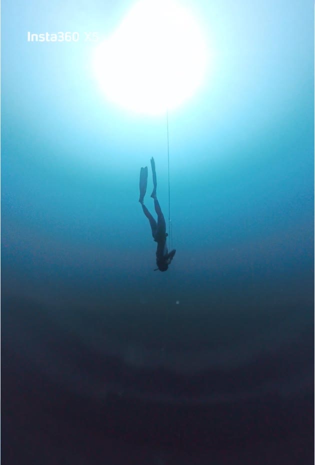 Freediver descending toward the sunburst